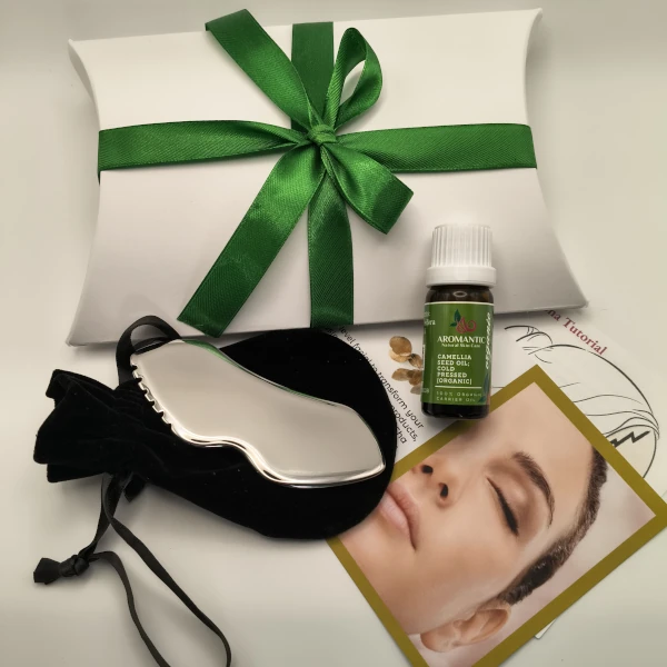 Glow Box Contents: Stainless Steel Gua Sha Tool, Instructions for use, vial of facial oil, pillow box tied with a ribbon